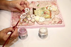 Eine Frau malt einen Holzauschnitt für einen dekorierten Bilderrahmen.