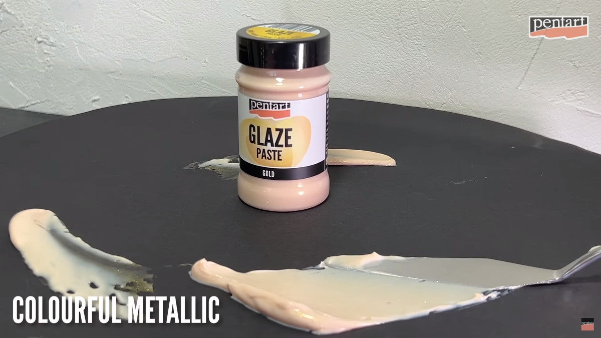 Pentart Glaze paste gold auf einer schwarzen Oberfläche mit einem Spachtel verstrichen