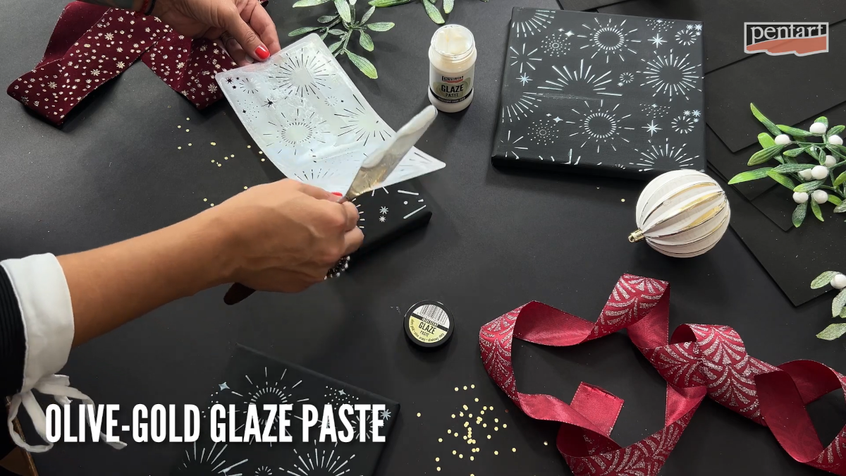 Eine Frau schabloniert einen schwarzen Keilrahmen mit pentart Glaze Paste